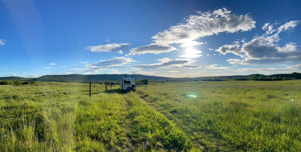 Blue sky and green field with RV.