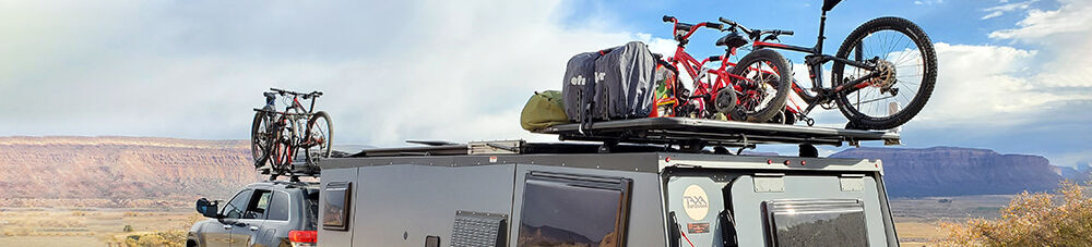 Platform racks mounted on Taxa Mantis and Jeep, holding bikes and other cargo.