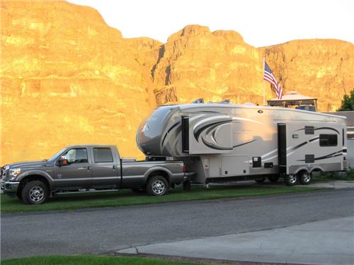Truck towing fifth wheel trailer in front of mountains