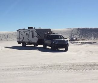 Truck pulling trailer in desert.