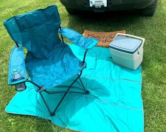 Picnic blanket and camping chair near car camp