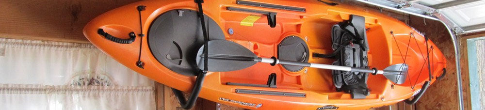 Orange kayak stored on garage wall.