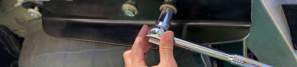 Hand holding a ratchet and socket up to a bolt.