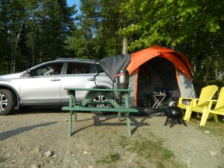 SUV with tent set up at campsite