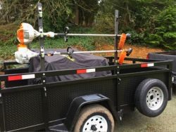 black utility trailer hauling lawn equipment. 